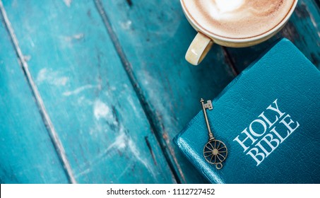 A Key Is On The Holy Bible With Green Wooden Background. 