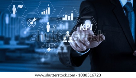 Key Performance Indicator (KPI) workinng with Business Intelligence (BI) metrics to measure achievement and planned target.Businessman hand pressing an imaginary button on virtual screen.