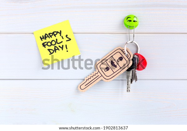 Key\
ring hung on the wall with a car key made of cardboard as a joke\
for the celebration of Fool\'s Day. Space for\
text.