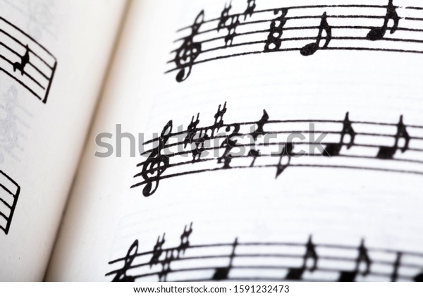 Key signature symbol and violin clef. Musical\
notation macro, closeup. Single line sheet music detail example,\
playing an instrument, learning theory abstract concept, music\
background, open book