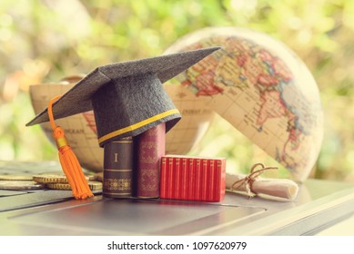 Key success in graduate study abroad program and open or expand world view experience concept : Graduation cap or hat, certificate or diploma, mini text books on a laptop computer, a half world globe.