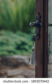 Key with a tassel key ring in the open door leading to the garden, selective focus.