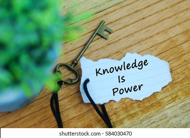 Key and torn paper with text knowledge is power on wooden background