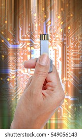 Key USB data storage in hand against bright light and circuit background.
