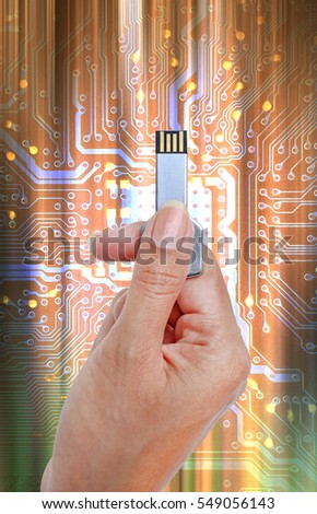 Key USB data storage in hand against bright light and circuit background.