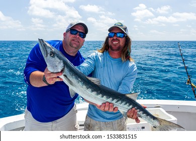 Key West, FL / USA - Oct. 9, 2019: Keaton Cook (right), Mate on the charter fishing vessel "Reef Runner," helps hold a barracuda with fisherman, George Wilson.