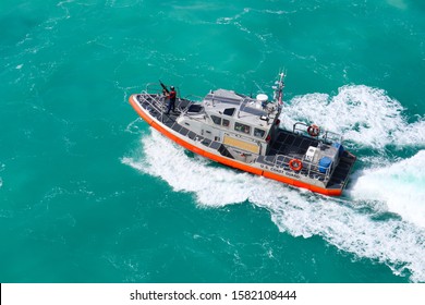 KEY WEST, FLORIDA/USA - NOVEMBER 12, 2019:  Aerial View Of An Armed Officer On A U.S. Coast Guard Vessel As It Speeds Through The Ocean.