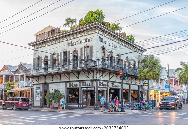 Key West, USA -\
January 24, 2021: Corner of Duval and Caroline street road\
intersection with people walking by The Bull and Whistle bar open\
air restaurant in summer in\
Florida
