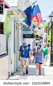 Key West, USA - May 1, 2018: People, Couple Walking On Duval Street Sidewalk Road With Gay Visitor Center, Bars, Restaurants, Cafes In Florida City Travel, Sunny Day On Street