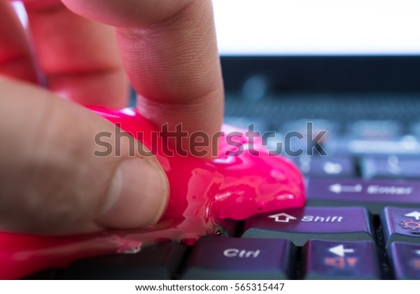 Keyboard\
cleaning gel in work. Hand and pink\
gel.