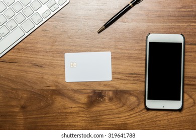 Keyboard, Credit Card, Pen And Smartphone On Wooden Office Table. Top View.