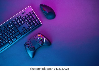 Keyboard, Mouse And Joystick On Violet Table Background.