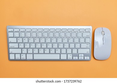 The keyboard and mouse are white on an orange table. Close up.
