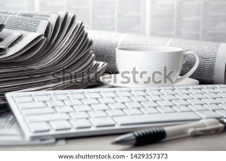 keyboard on newspapers and a cup of coffee on the table closeup
