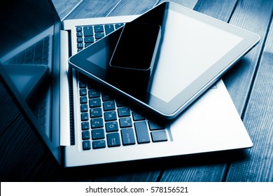 keyboard with phone and tablet pc on wooden desk. Blue toned 