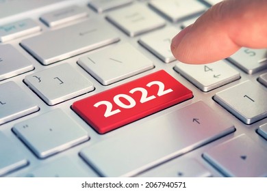Keyboard with text HAPPY 2022 and finger pushing the enter button. Color button on the gray silver keyboard of modern ultrabook. caption on the button - Shutterstock ID 2067940571