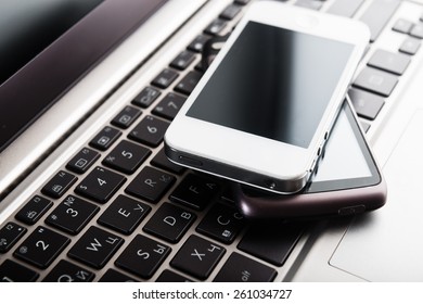 Keyboard With Two Phones On Wooden Desk 