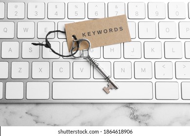 Keyboard, vintage key and tag with word KEYWORDS on white marble table, top view - Shutterstock ID 1864618906