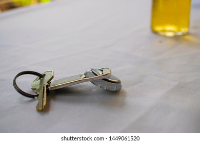 Keychain With Bottle Opener And A Beer In The Background.