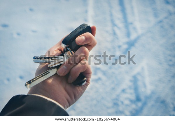 keychain with car keys in hand on the\
background of snow. trying to start a car in\
winter