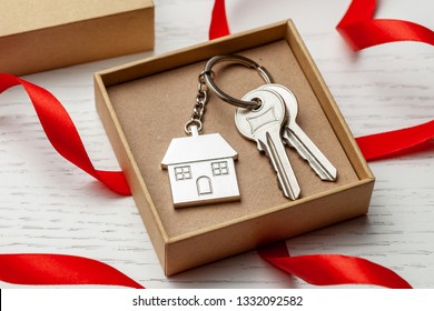 Keychain house and keys with red ribbon and gift box on white wooden background - Powered by Shutterstock