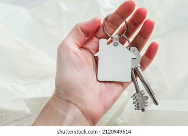 Keychain house shaped mockup in hand. Blank white sublimation keychain. Copy space.