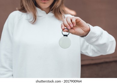 Keychain mockup in woman's hand. Blank round white sublimation keychain. Copy space.