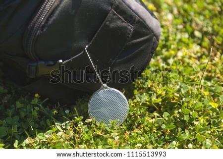 Keychain-reflector on a backpack in a city park, safety on the road, social responsibility