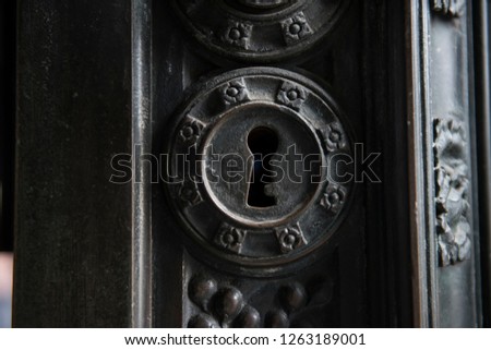 Keyhole on an ancient architectural door of an old church. The brass handle looks  stunning along with the black wooden architecture, revealing medieval style.