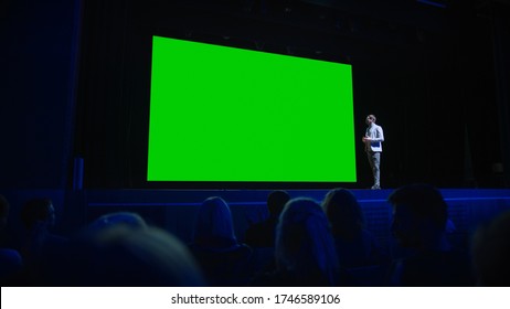 Keynote Speaker Announces New Product To The Audience, Behind Him Movie Theater With Green Screen, Mock-up, Chroma Key. Business Conference Live Event Or Device Reveal