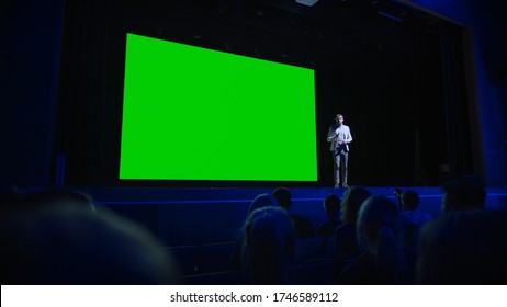 Keynote Speaker Announces New Product To The Audience, Behind Him Movie Theater With Green Screen, Mock-up, Chroma Key. Business Conference Live Event Or Device Reveal