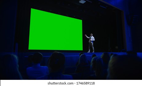 Keynote Speaker Announces New Product To The Audience, Behind Him Movie Theater With Green Screen, Mock-up, Chroma Key. Business Conference Live Event Or Device Reveal