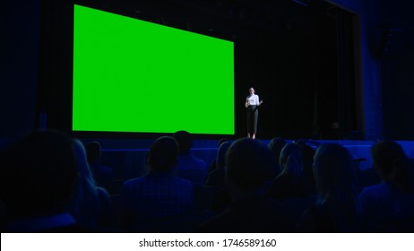 Keynote Speaker Announces New Product To The Audience, Behind Her Movie Theater With Green Screen, Mock-up, Chroma Key. Female CEO Shows Leadership On Business Live Event Or Device Reveal