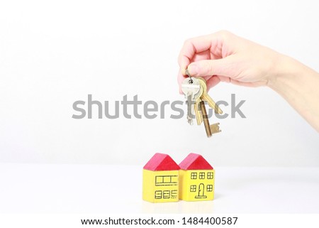keys in hand representing property purchase with miniature toy block houses on table with white background and people body part stock image stock photo