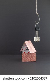 The Keys To The House Hang Like Bait On A Fishing Hook Above The House Of Cards. Background Picture. Space For Printing Text.