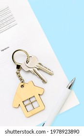 Keys and house shaped keychain on real estate mortgage loan document, contract agreement to buy or construction new home, insurance, registration of lease, rent apartments. Vertical blue background.