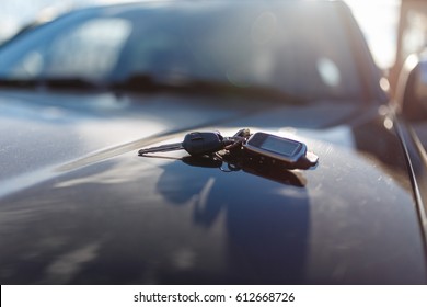 Keys with immobilizer on the car hood in the background of the front Windows. Beautiful spring light and the sun.