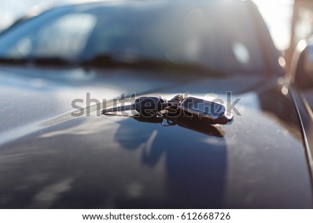 Keys with immobilizer on the car hood in the background of the front Windows. Beautiful spring light and the sun.