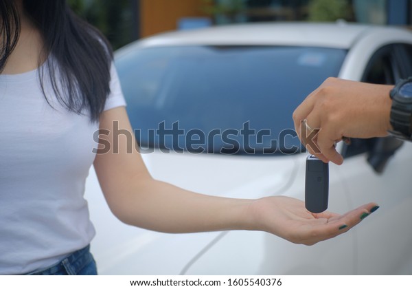 Keys from new car, \
salesman transfer the car key in hand of customer in casual wear on\
dealership background.