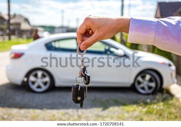 Keys from new car, young\
salesman transfer the car key in hand of customer in casual\
wear.