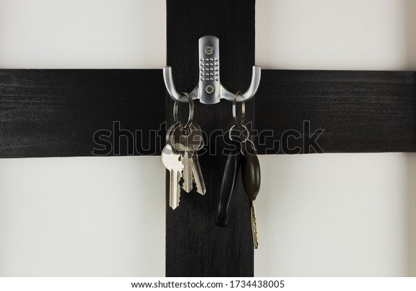 Keys on a hanger from a car and apartment. Keys\
hang on a wooden, black\
hanger