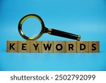 Keywords with wooden blocks alphabet letters and Magnifying glass on blue background