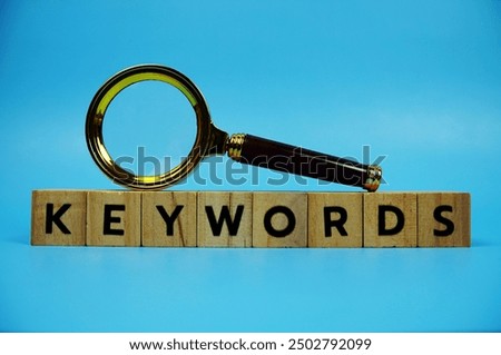 Keywords with wooden blocks alphabet letters and Magnifying glass on blue background
