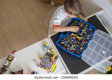 Khabarovsk, Russia, August 02, 2022. Cut Child Male Sorting Heap Of Small Lego Pieces Into Boxes. Constructor Playthings Comfortable Storage System Organizing