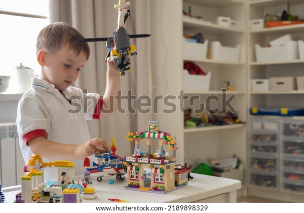 Khabarovsk, Russia, August 02, 2022. Enthusiastic\
male kid constructing toy helicopter use Lego Classic at home. Cute\
boy child playing constructor pieces building vehicle\
transportation toy