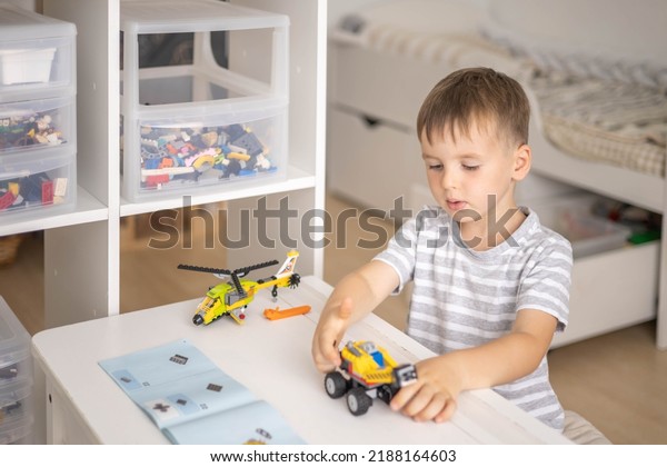 Khabarovsk, Russia, August 07, 2022.  Male kid\
constructing according to instructions toy helicopter and use Lego\
Classic. Cute boy child playing constructor pieces building vehicle\
transportation toy