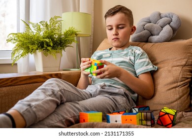 Khabarovsk, Russia, February 18, 2022. Portrait Confident Frowning Male Teenager Brainstorming Assembling Rubik's Cube Solving Mind Logic Decision. Male Adolescent Kid Thinking With Puzzle Development