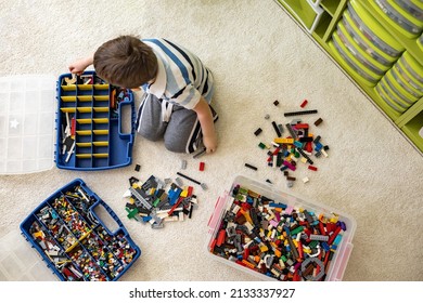 Khabarovsk, Russia, February 18, 2022. Boy Sorting Lego Colored Pieces Into Boxes With Small Cells. Constructor Toy Storage System, Home Cleanup. Male Kid Putting Blocks To Containers At Childish Room