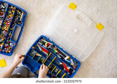 Khabarovsk, Russia, February 18, 2022. Boy Sorting Lego Colored Pieces Into Boxes With Small Cells. Constructor Toy Storage System, Home Cleanup. Male Kid Putting Blocks To Containers At Childish Room