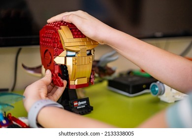Khabarovsk, Russia, February 18, 2022. Closeup Male Kid Hands Constructing Iron Man Head Lego Details. Child Boy Arms Playing With Interesting Entertainment Constructor Pieces Development Game